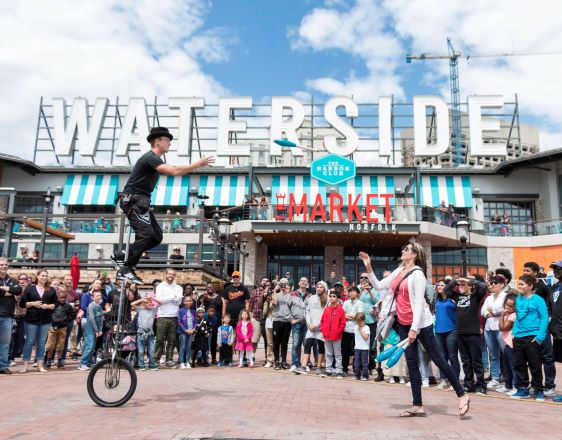 Waterside District after renovation. Man juggling and riding unicylce in front of a crowd.